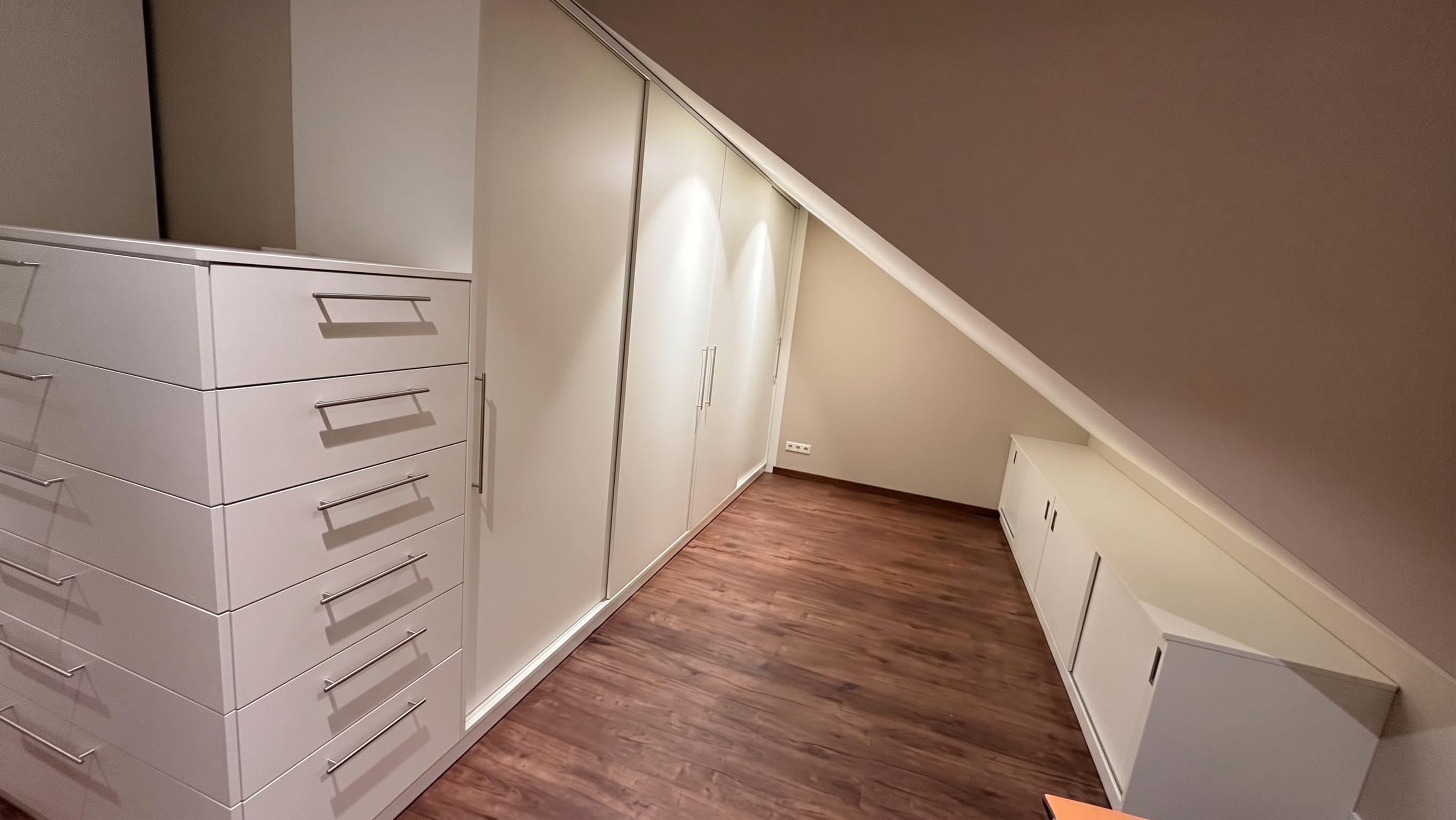Weiße Einbauschränke, Kommode und Sideboard unter einer Dachschräge