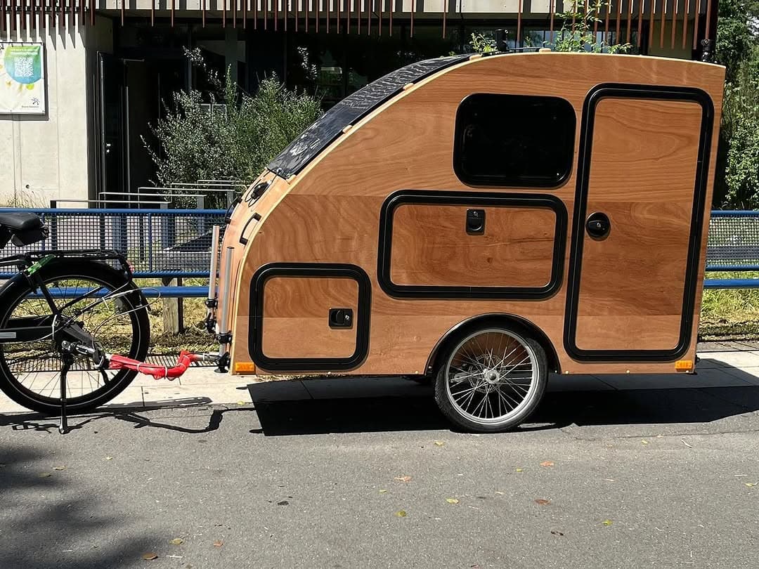 Fahrrad-Camper i:woody aus Holz hinter einem E-Bike, Seitenansicht