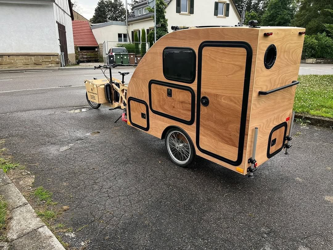 Fahrrad-Camper i:woody aus Holz hinter einem Lastenrad